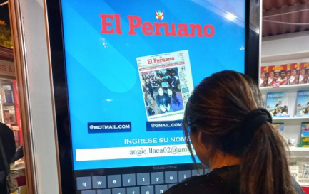 Joven en el stand espera por una foto con la portada digital de El Peruano